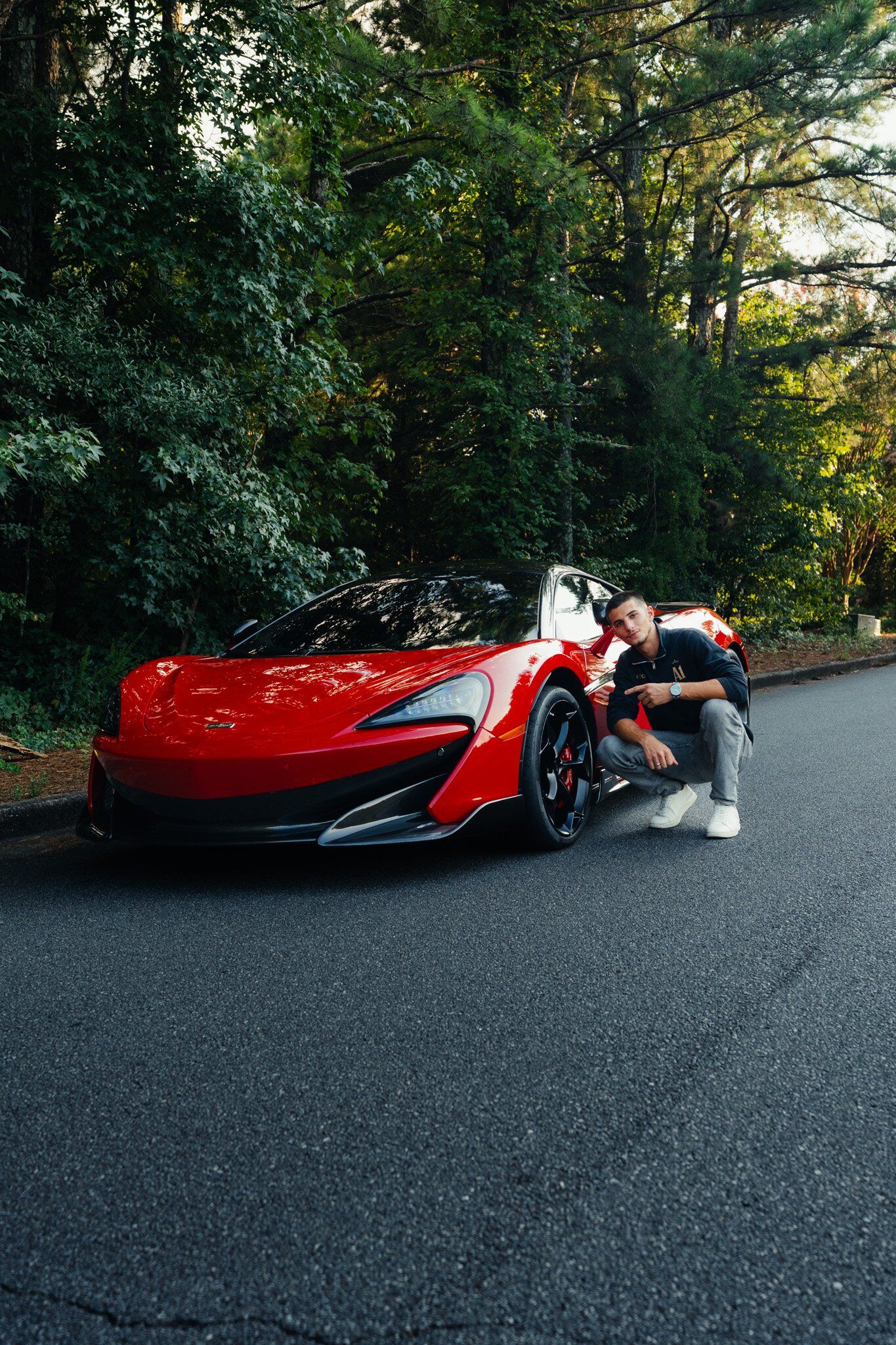 A member of the A1 Detailz team crouched beside a red McLaren 600LT